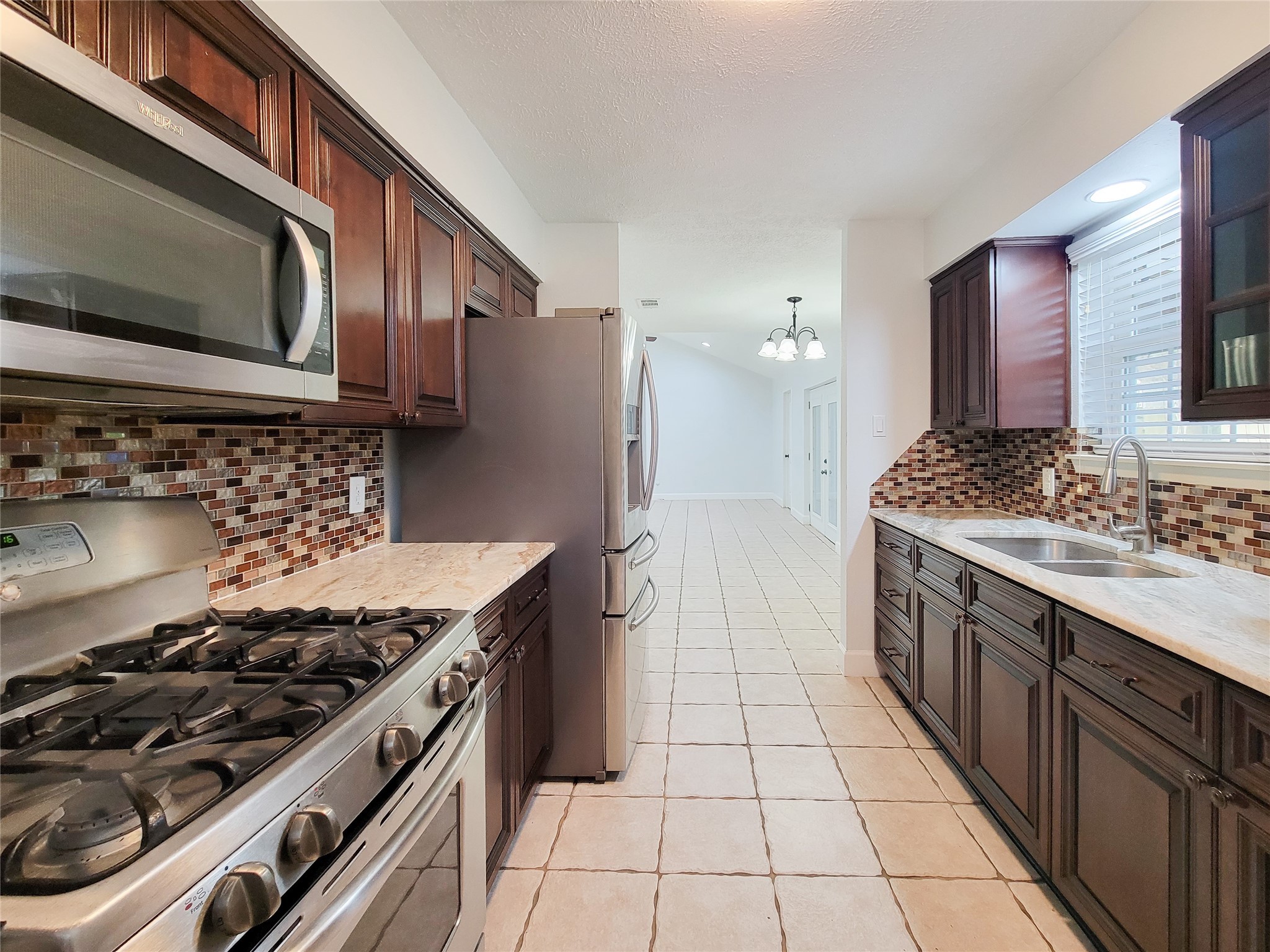 3434 Almondwood Drive Spring, TX 77389 - Photo 14 of 37 a kitchen with stainless steel appliances a stove a sink and a microwave