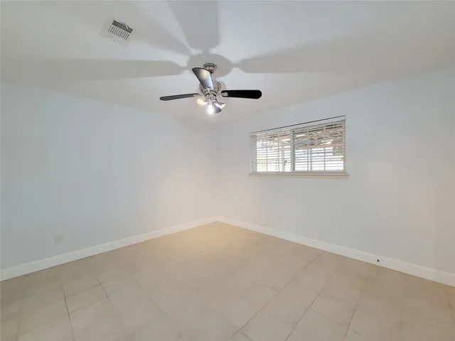 an empty room with windows and ceiling fan