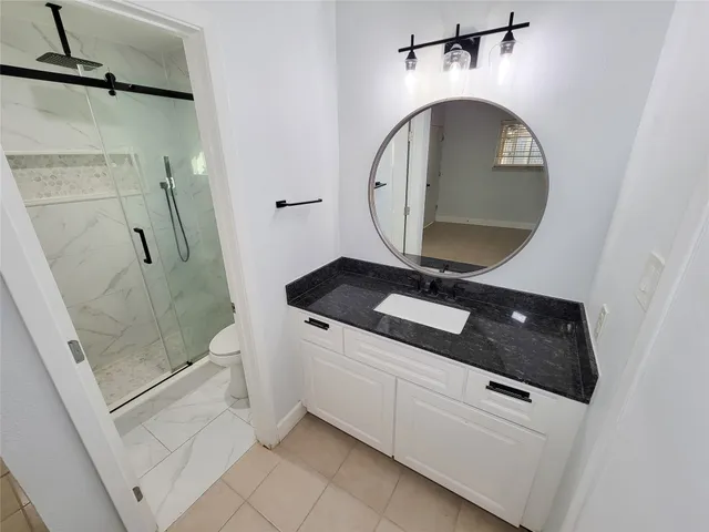 a bathroom with a granite countertop sink a toilet and shower
