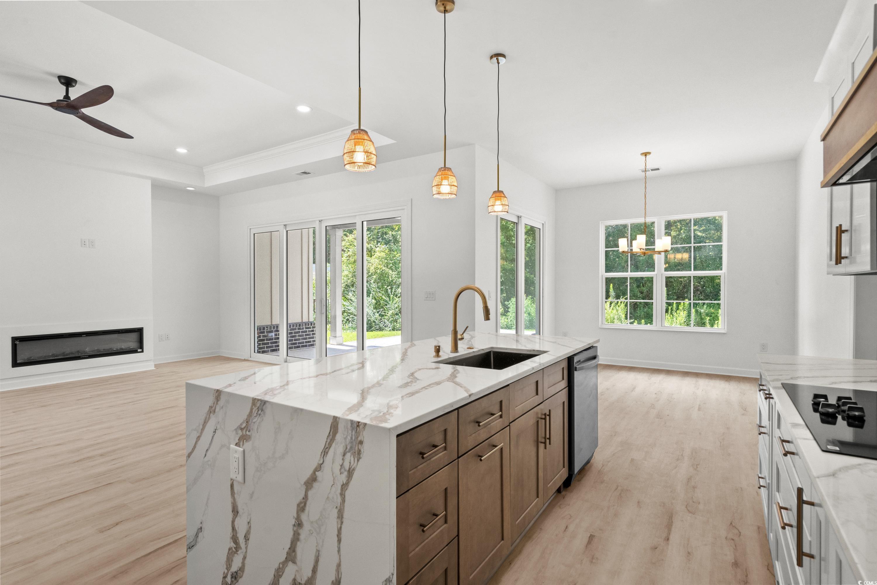 232 Ole Maple Street Loris, SC 29569 - Photo 13 of 40 Kitchen featuring decorative light fixtures, light stone countertops, light wood finished floors, a glass covered fireplace, and brown cabinets