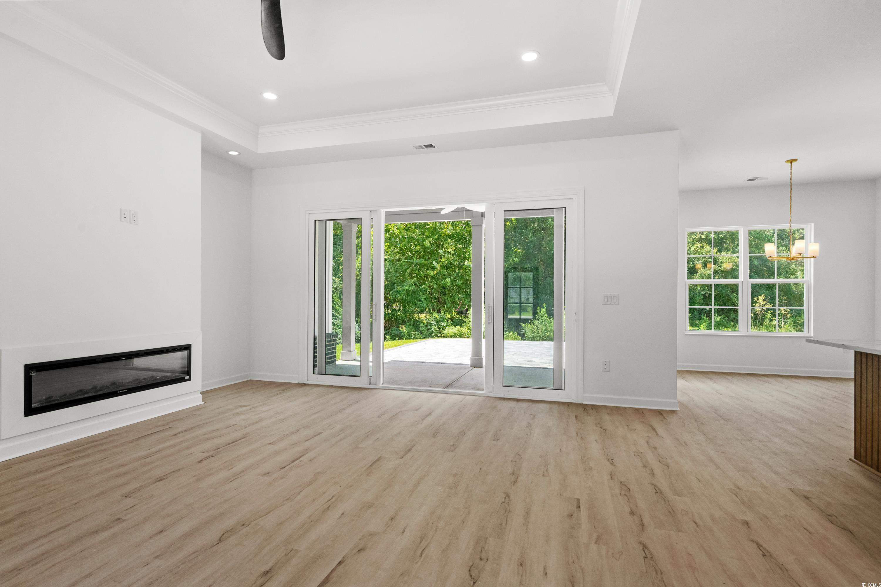 232 Ole Maple Street Loris, SC 29569 - Photo 15 of 40 Unfurnished living room with a tray ceiling, light wood-type flooring, plenty of natural light, ornamental molding, and recessed lighting