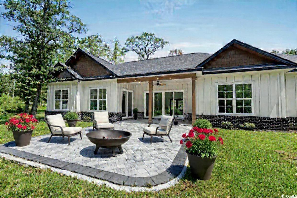 232 Ole Maple Street Loris, SC 29569 - Photo 16 of 39 Rear view of property featuring board and batten siding, a patio, ceiling fan, an outdoor fire pit, and brick siding