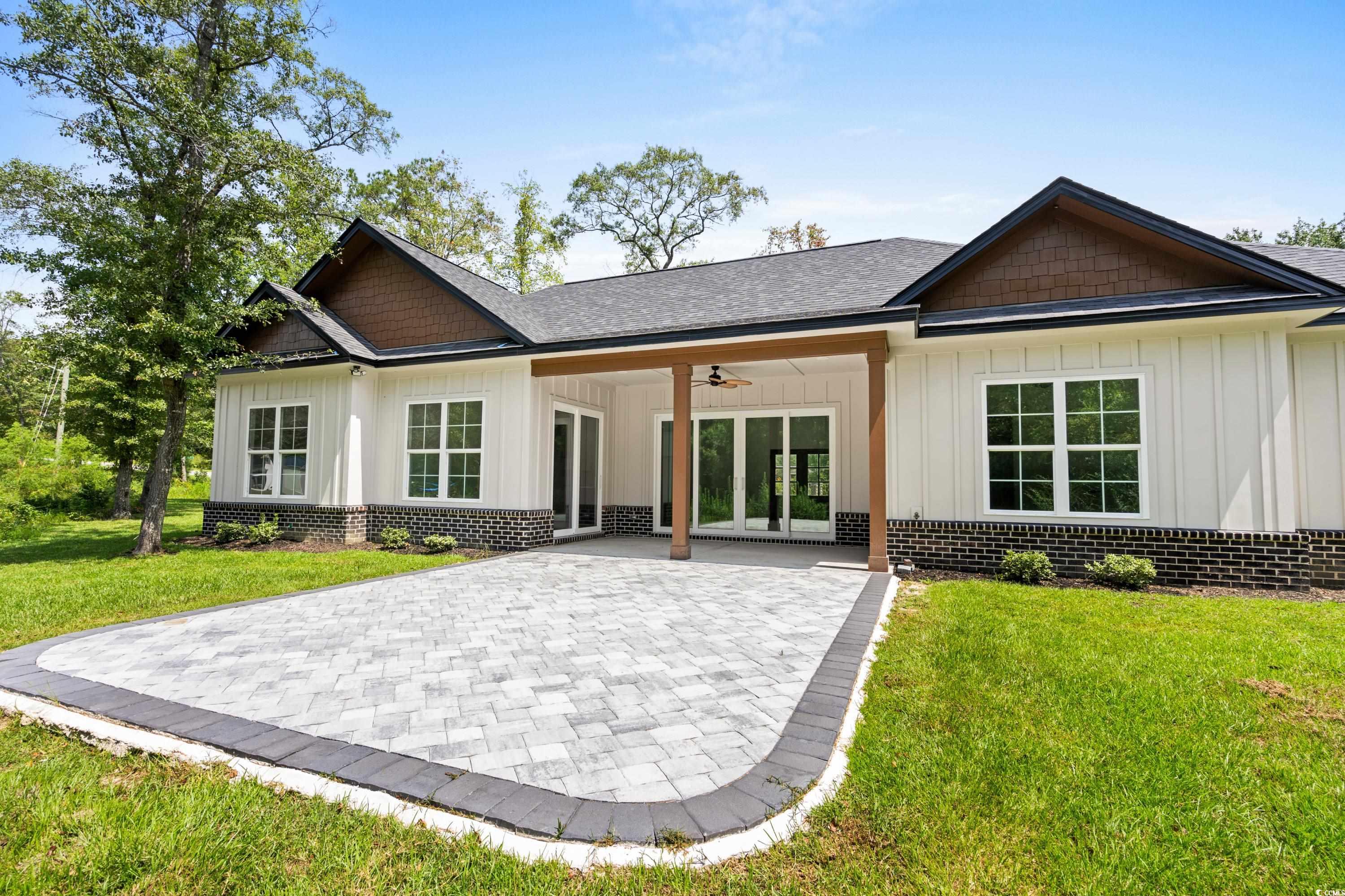232 Ole Maple Street Loris, SC 29569 - Photo 18 of 40 Rear view of house with board and batten siding, a ceiling fan, a lawn, and brick siding