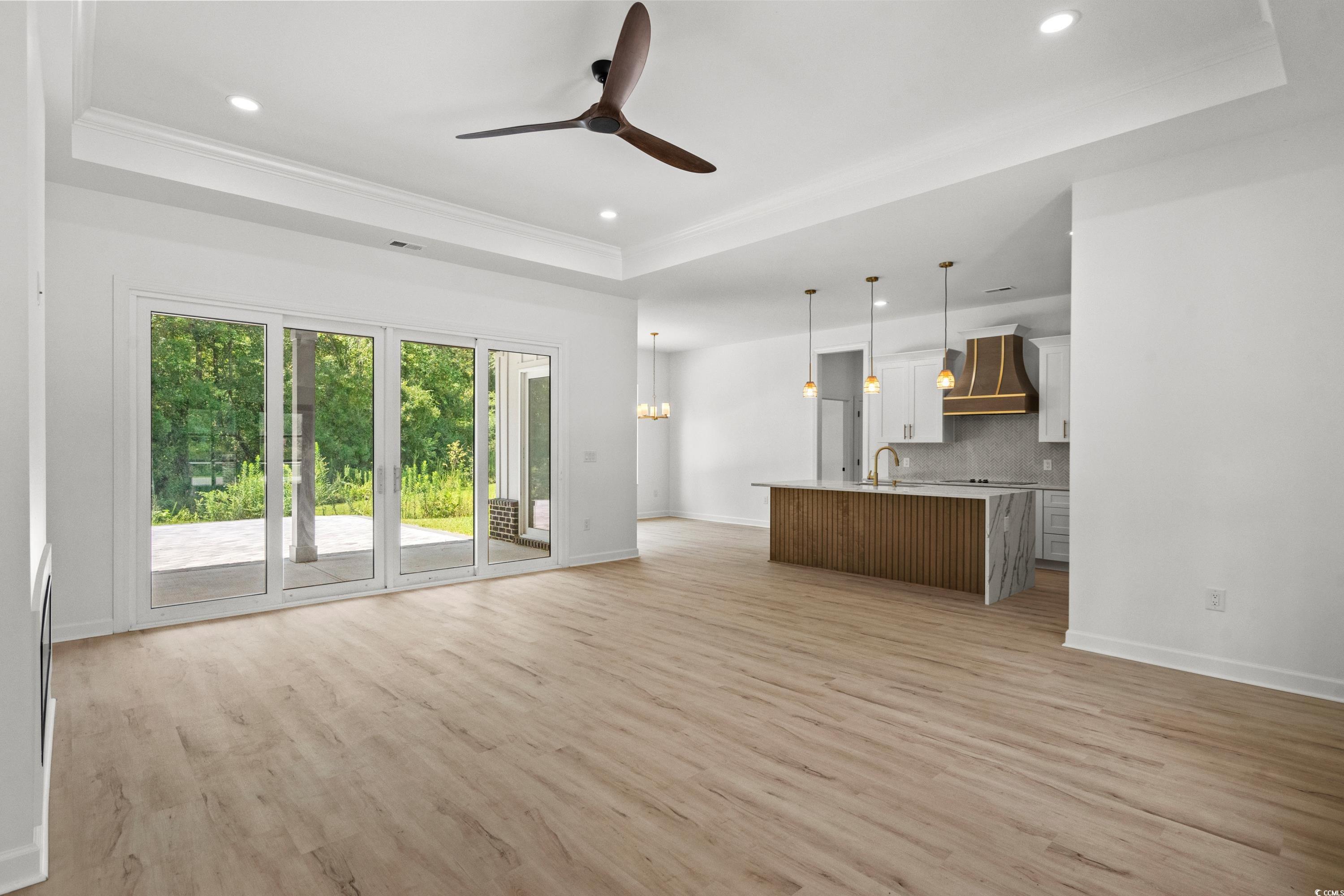 232 Ole Maple Street Loris, SC 29569 - Photo 6 of 40 Unfurnished living room with a tray ceiling, light wood finished floors, a ceiling fan, recessed lighting, and crown molding