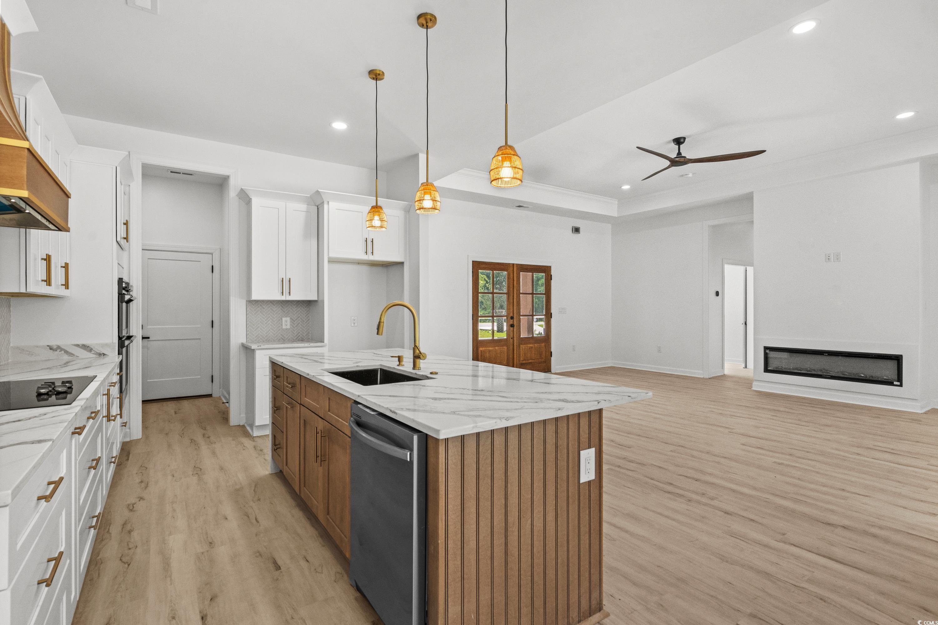 232 Ole Maple Street Loris, SC 29569 - Photo 39 of 40 Kitchen with light wood-style floors, hanging light fixtures, open floor plan, brown cabinets, and backsplash