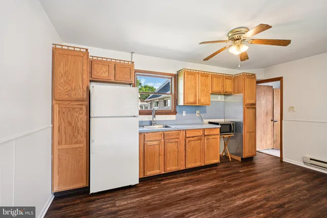 a view of a room with wooden floor a ceiling fan and windows