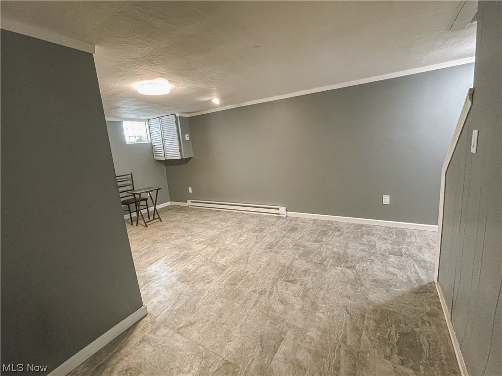 24709 Emery Road Warrensville Heights, OH 44128 - Photo 29 of 34 Basement with a baseboard heating unit and crown molding
