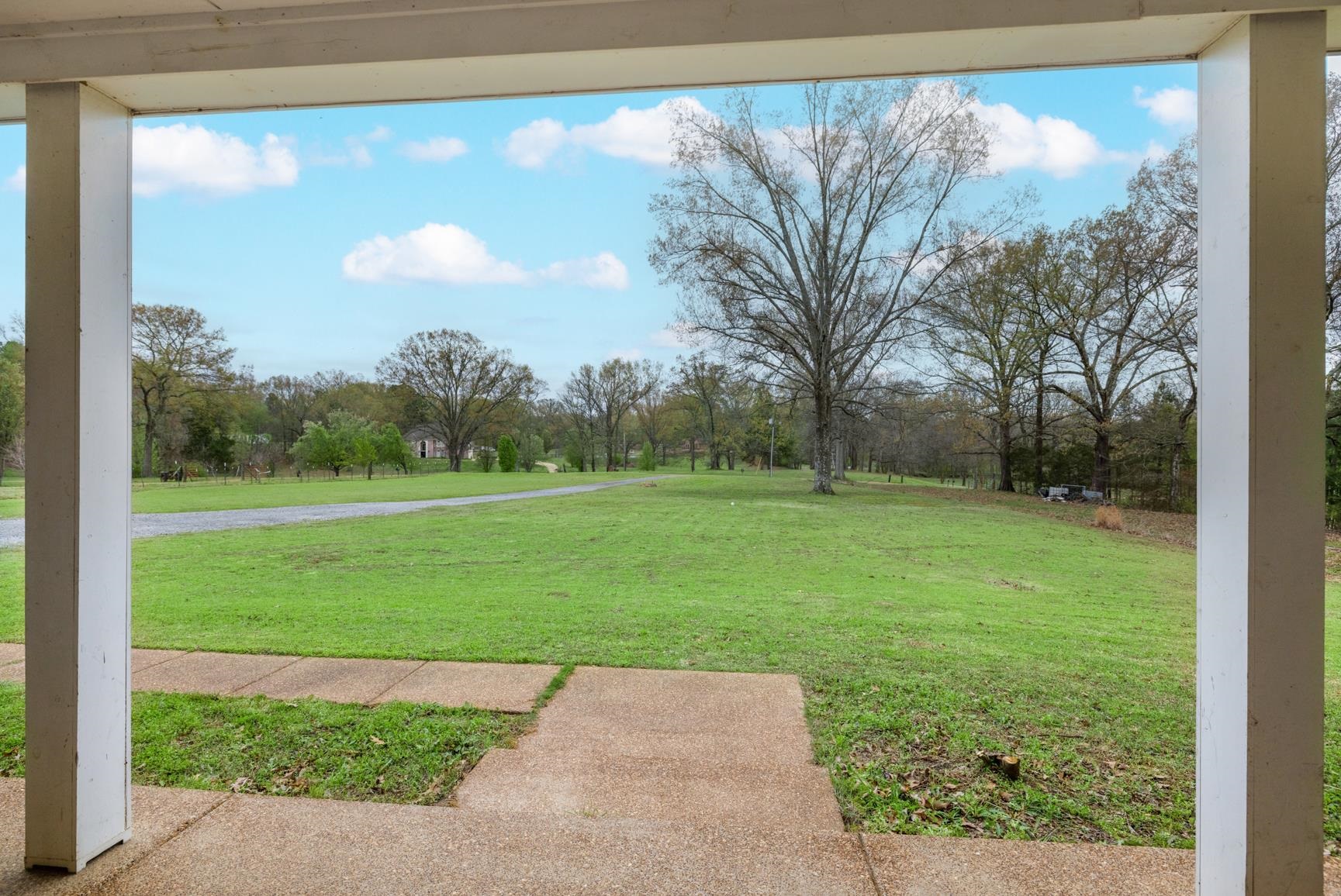 504 Bankston Road Nesbit, MS 38651 - Photo 6 of 39 Covered porch with white support columns, concrete flooring, and an expansive grassy lawn with mature trees