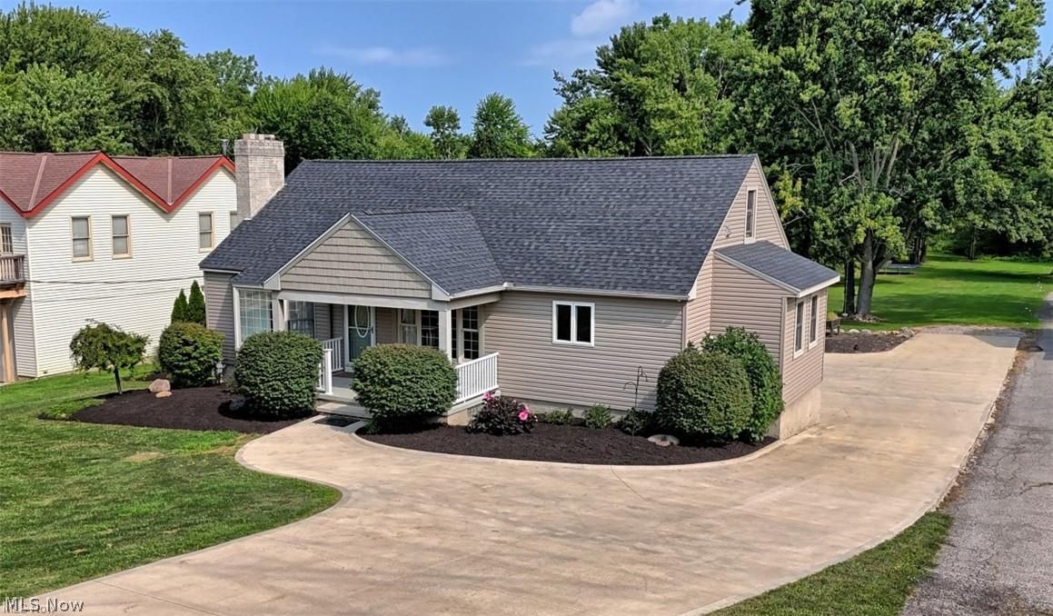 Cape Cod style home featuring a covered front porch, a shingle roof, and a stone chimney