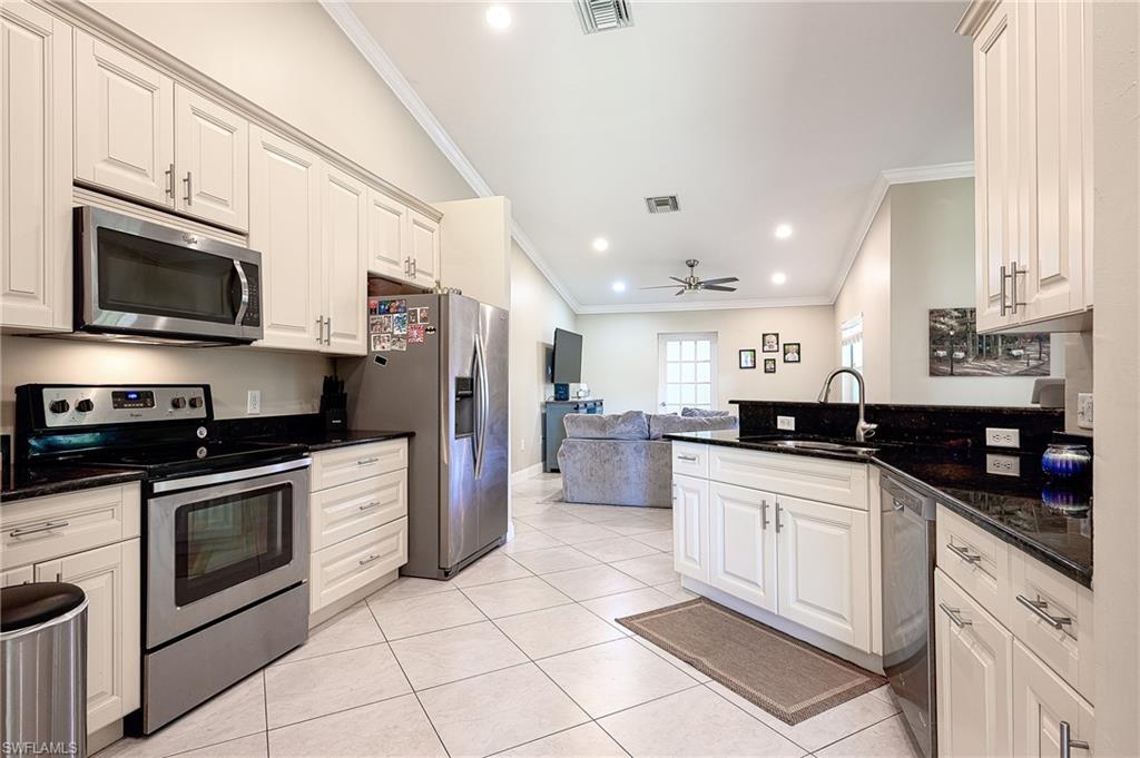 10058 Boca Circle Naples, FL 34109 - Photo 11 of 33 a kitchen with stainless steel appliances granite countertop a sink dishwasher stove and refrigerator