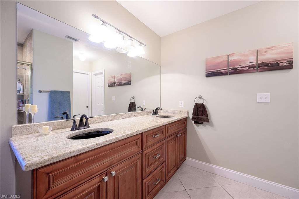 10058 Boca Circle Naples, FL 34109 - Photo 32 of 33 a bathroom with a granite countertop sink and a mirror