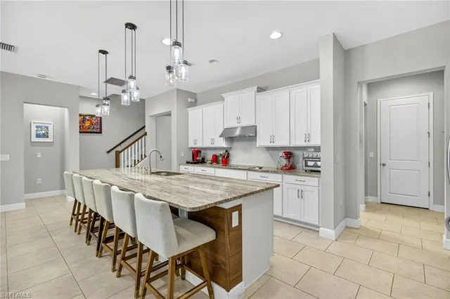 a kitchen with stainless steel appliances kitchen island granite countertop a table chairs and cabinets
