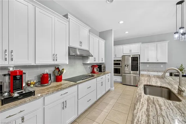 a kitchen with kitchen island granite countertop a sink stainless steel appliances and cabinets