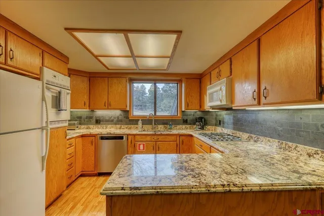 a kitchen with stainless steel appliances granite countertop sink stove and refrigerator