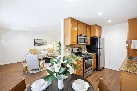 a kitchen with stainless steel appliances granite countertop a sink a stove a refrigerator a microwave a dining table and chairs with wooden floor