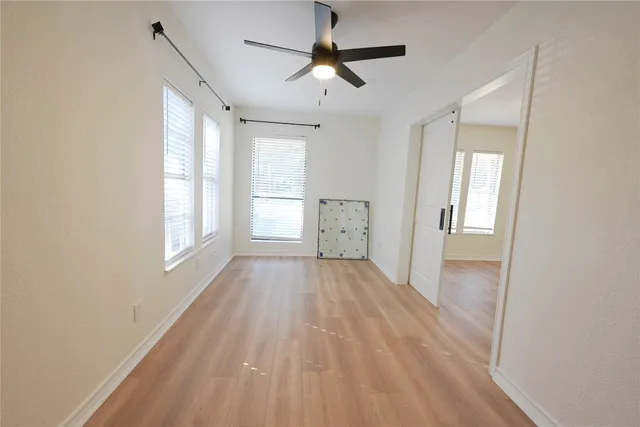 a view of empty room with wooden floor and fan