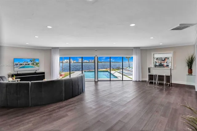 a living room with furniture a flat screen tv and floor to ceiling window