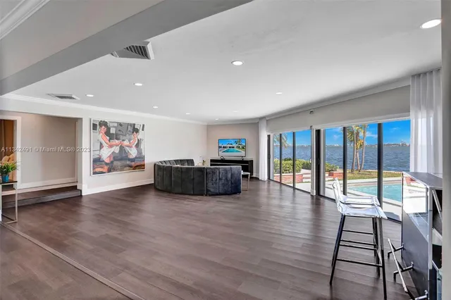 a living room with furniture floor to ceiling window and wooden floor