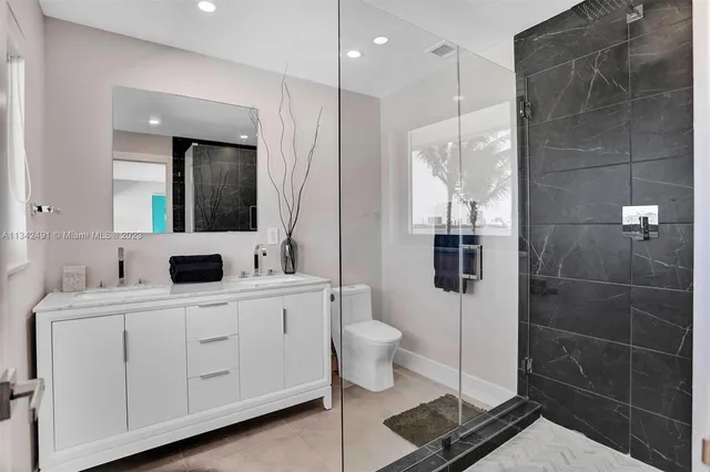 a bathroom with a double vanity sink toilet and mirror