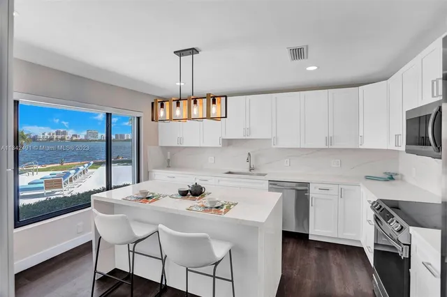 a kitchen with stainless steel appliances a sink a stove a table and chairs in it