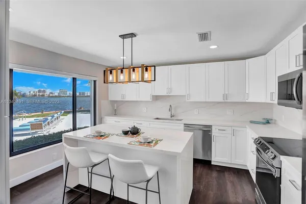 a kitchen with stainless steel appliances a sink a stove a table and chairs in it