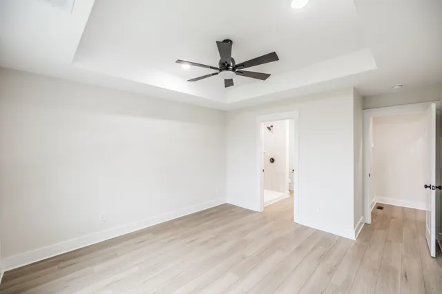an empty room with wooden floor and a ceiling fan