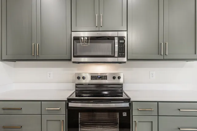 a kitchen with stainless steel appliances granite countertop white cabinets and a stove top oven