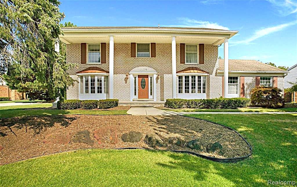 1114 Chaffer Drive Rochester, MI 48306 - Photo 1 of 50 Elegant brick Colonial with classic architectural details, featuring a welcoming front entrance with sidelights, white columns framing the covered portico, and multi-pane windows