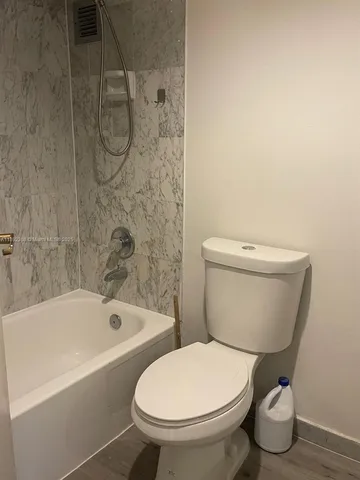 a white toilet sitting next to a bath tub and a shower