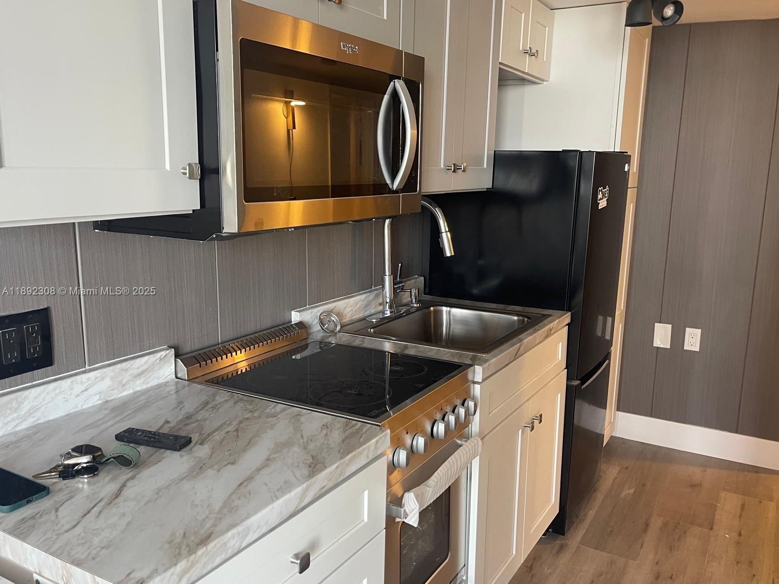 555 Northeast 15th Street, Unit 416 Miami, FL 33132 - Photo 7 of 13 a kitchen with a sink and a stove with wooden floor