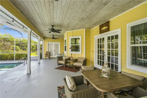 a dining room with furniture large windows and wooden floor