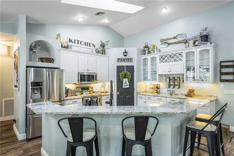 a kitchen with granite countertop a table chairs stove and refrigerator