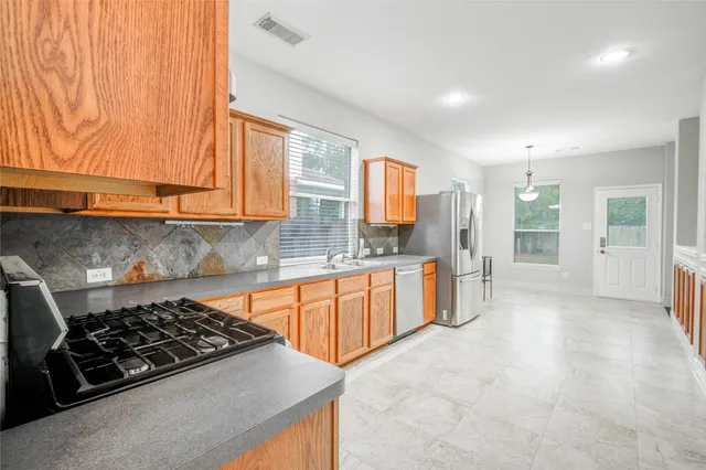 a kitchen with stainless steel appliances a stove a sink a refrigerator and cabinets