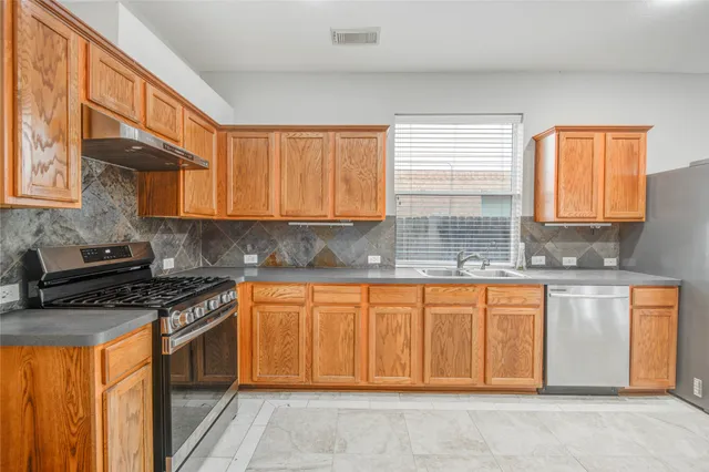 a kitchen with stainless steel appliances granite countertop a stove a sink dishwasher and cabinets with wooden floor