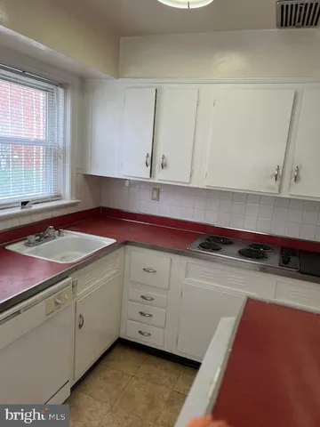a kitchen with stainless steel appliances a sink dishwasher and white cabinets