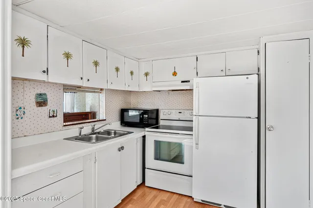 a kitchen with refrigerator a stove a sink and white cabinets
