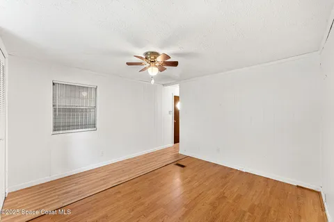 a view of wooden floor and chandelier fan in a room
