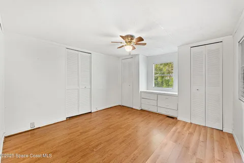 an empty room with windows and chandelier fan
