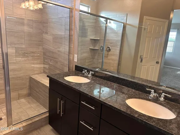 a bathroom with a granite countertop double vanity sink and a mirror