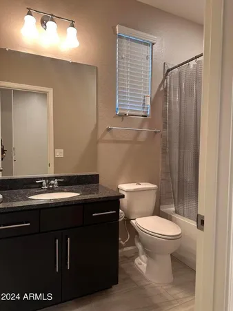 a bathroom with a granite countertop toilet sink and mirror