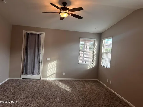 an empty room with windows and fan