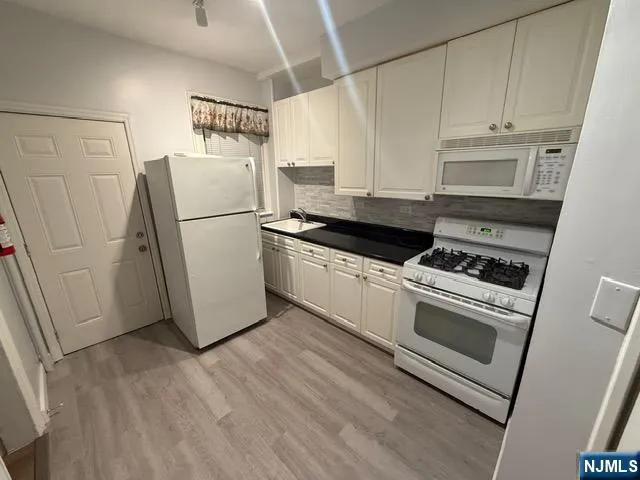 a kitchen with a refrigerator stove and white cabinets