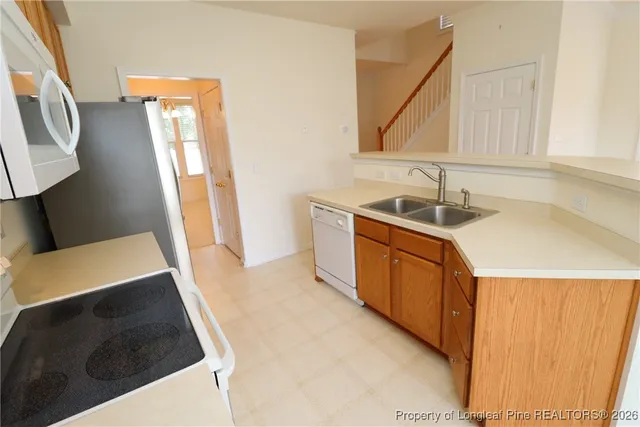 a kitchen with stainless steel appliances granite countertop a refrigerator stove top oven with a sink and dishwasher