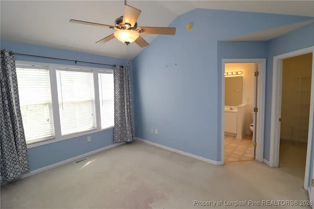 an empty room with a chandelier fan and a window