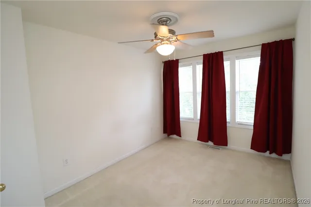 an empty room with a chandelier fan and wooden floor