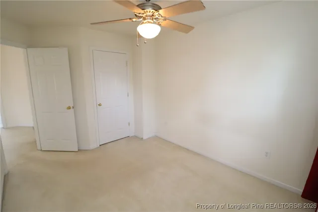 an empty room with a chandelier fan and wooden floor