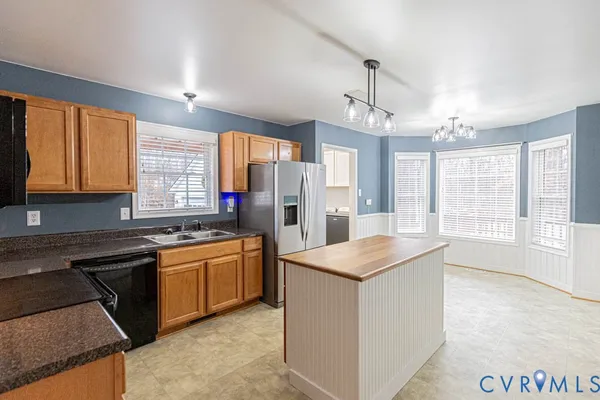 a kitchen with stainless steel appliances granite countertop a stove a sink dishwasher a refrigerator and white cabinets with wooden floor