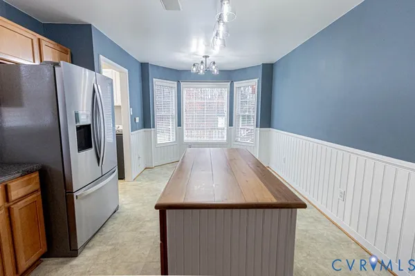 a view of a kitchen with a refrigerator a kitchen island wooden floor and windows