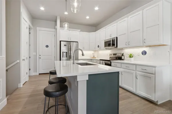 a kitchen with stainless steel appliances kitchen island granite countertop a refrigerator a sink dishwasher a stove and white cabinets with wooden floor