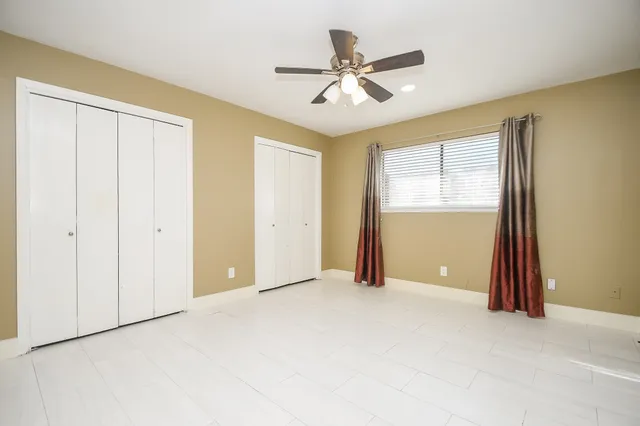 an empty room with windows and fan